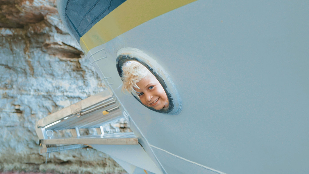 Enfant se penchant par-dessus le bastingage du bateau pour regarder la mer